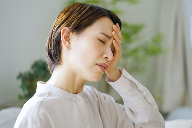 頭痛がして頭を抑えている人
